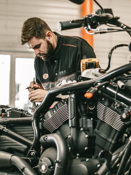 Motorcycle mechanic repairing electronics sports black bike. Motorcycle mechanic repairing electronics sports black bike. Handsome mechanic working in auto repair shop.